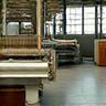 最新の自動織機と伝統的な手織り機が並ぶ工場風景